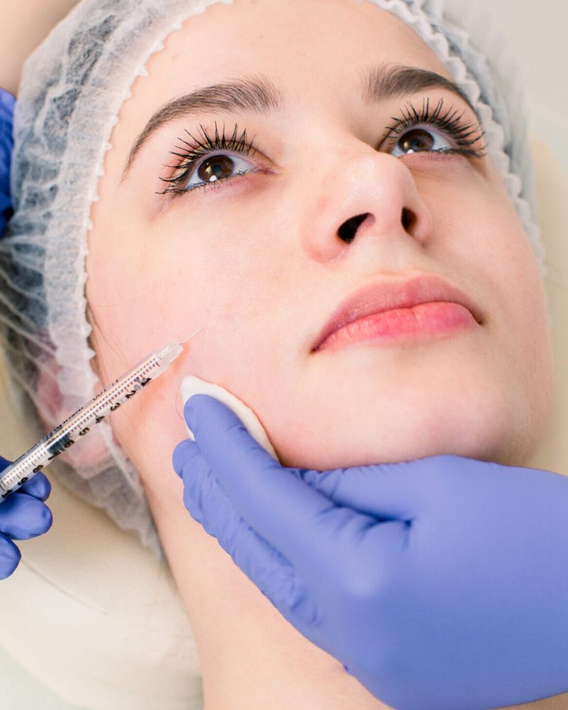 Doctor injecting in a beautiful face of a young woman. Plastic surgery concept